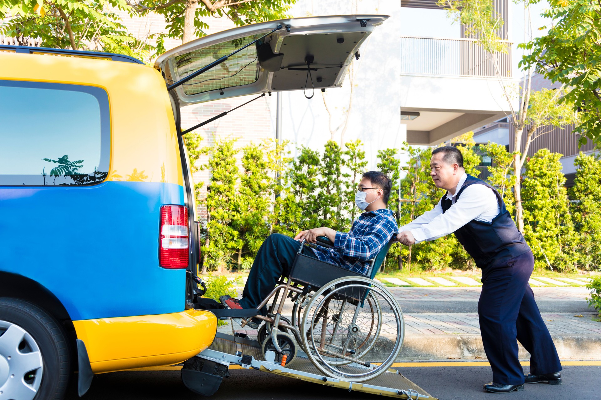 driver helping man on wheelchair getting into taxi